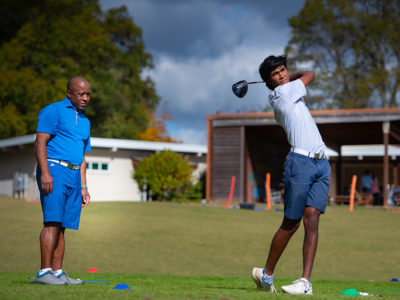 First Tee participant practicing their golf swing with a mentor.